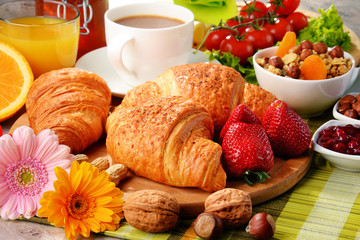 Breakfast consisting of croissants, coffee, fruits, orange juice