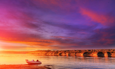 majestic landskape.  fantastic foggy sunset over the river with colorful clouds on the sky. picturesque nature landscape. speed inflatable boat on the river. soft light effect,
