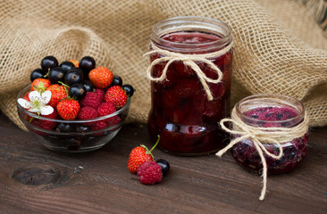 strawberry, blackcurrant and raspberry. Berry jam in a jar on wooden background