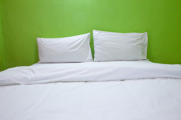 An unmade bed with white linens background green