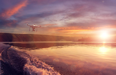  quadrocopter drone with remote control against colorfull sunset on river. close-up texture of...