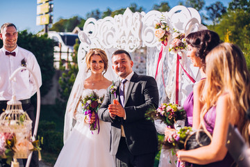 Bride and groom on wedding ceremony near decorated arch and photozone outdoor