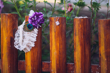 Beautiful wedding garter in violet color outdoor on wooden fence.