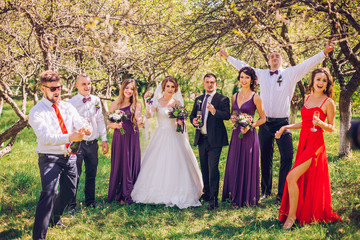 bride and groom with bridesmaids and groomsman having fun anf jump outdoor green park forest