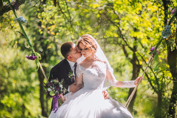 Happy Couple newlyweds in the woods, on a swing