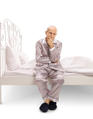 Pensive senior sitting on a bed