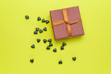 Small gift box with black hearts on a yellow background