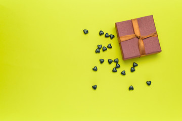 Small gift box with black hearts on a yellow background