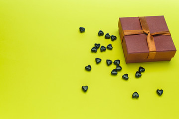 Small gift box with black hearts on a yellow background