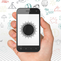 Tourism concept: Hand Holding Smartphone with Sun on display