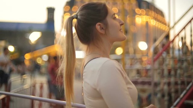 Closeup of beautiful elegant woman looking at merry-go-round carousel at evening