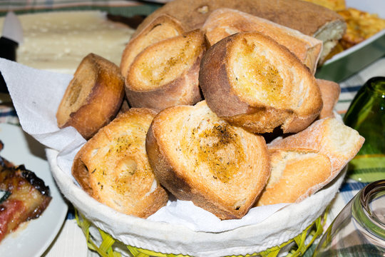 Cesto ripieno di panini e fette di pane tostato condito con olio e pepe 