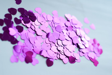 Colorful confetti on light background, little hearts rise up,