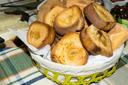 Cesto ripieno di panini e fette di pane tostato condito con olio e pepe 