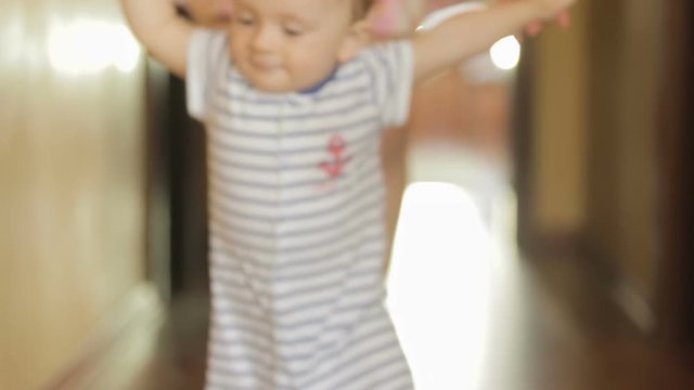 Happy smiling baby boy walking with mother at home