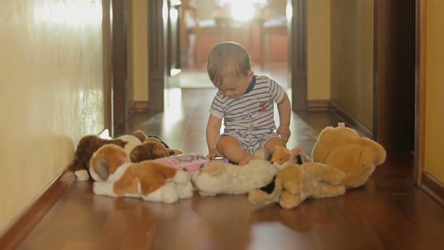 Cute smiling baby boy playing on floor with stuffed toys