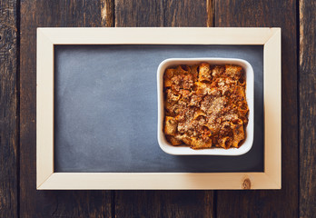 Baked pasta with mince, ragù sauce. Baking sheet on blackboard