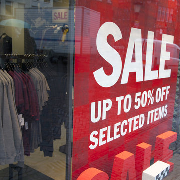 sale signs in display window of clothing store
