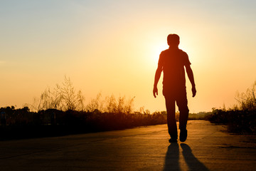 silhouette man walking on road at sunset background