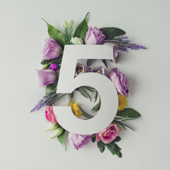 Creative layout with colorful flowers, leaves and number five. A