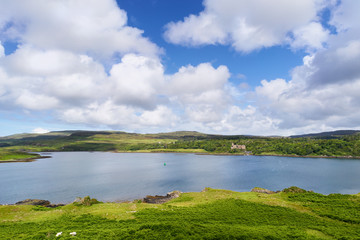 Blue skies and white clouds over Dunvegan Loch and Castle on the Isle of Skye, Scotland, UK. 
