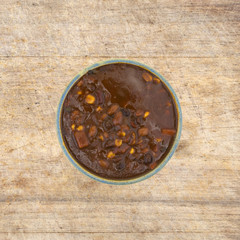 Vegetable chili in an old bowl on a rustic table.