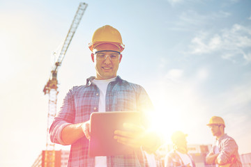 builder in hardhat with tablet pc at construction