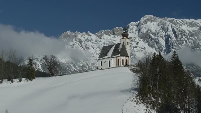 Church St. Nikolaus at a foothills. In the background the Hochkonig Mountains in Dienten,  Salzburger Land, Austria, Alps, Jan 2017 .