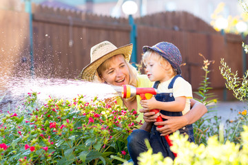Happy mother and child water in domestic garden