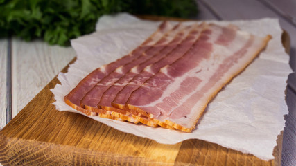 Fresh raw cold sliced bacon with fresh salad on the wood background closeup selective focuse