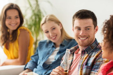 group of happy friends with beer talking at home