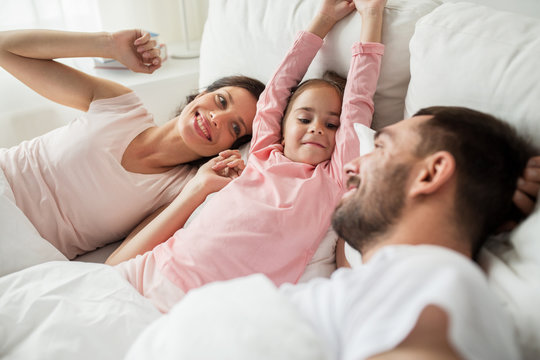 happy family waking up in bed at home