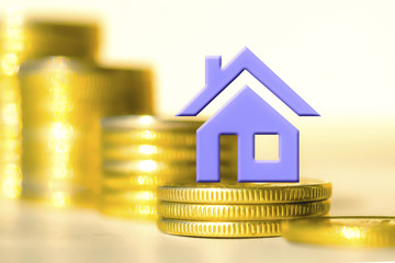 Blue house against the columns of coins .  The concept of financial instability on the market .