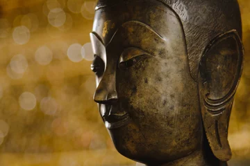 Papier Peint photo Lavable Bouddha gros plan sur le visage de la statue de la tête de bouddha avec un arrière-plan flou et un effet d& 39 éclairage. Statue de bouddha face à mise au point sélective.