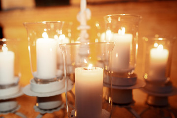 Large candleholder with white candles in glass vases stands outs