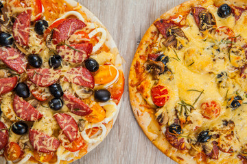 Top view two Pizza with mushrooms, olives and tomatoes, sausage. Rosemary and fresh vegetables. Freshly homemade