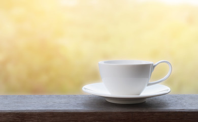 White coffee cup on wooden with sun light and blur background.