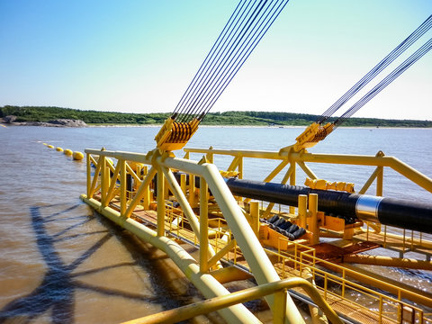 Laying of pipes with pipe-laying barge crane near the shore