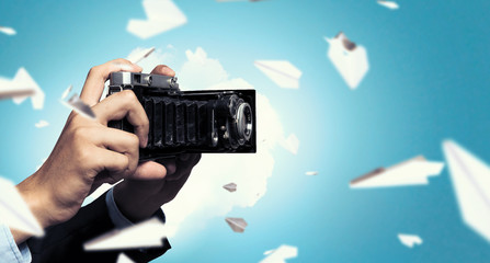 Businessman taking photo with vintage camera . Mixed media