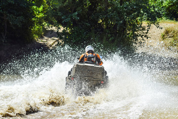 The man on the ATV crosses a stream. Tourist walks on a cross-country terrain