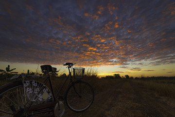 Fototapeta na wymiar Vintage bicycle on local road with sunrise light background