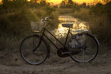 Fototapeta na wymiar Vintage bicycle on local road with sunrise light background