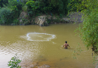 Unidentified man fishing by net at a part of river passing through Tu Le, Yen Bai, Vietnam