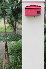 Red mailbox on white concrete pole.