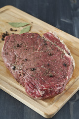 Piece of raw beef with spices on wooden board