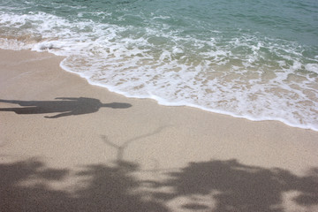Shadows of men and tree on the beach. 