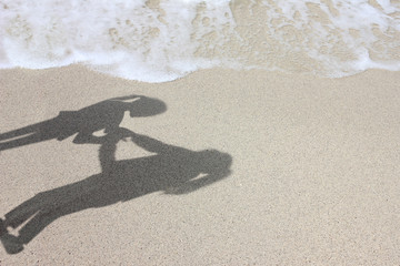 Shadow of a mother and daughter on the beach near the sea. 
