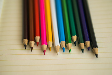 Obraz premium Color pencils on white notebook background.Close up.