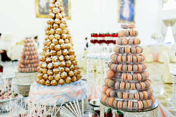 Pyramids of macaroons and eclairs stand on luxury served candy b