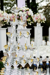 Pyramid of cocktail glasses stands outside before white pillars